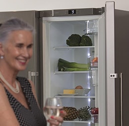 Freestanding fridge in background of grandma enjoying wine